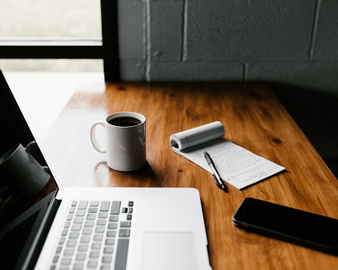Un bureau avec un ordinateur portable, un carnet et un stylo
