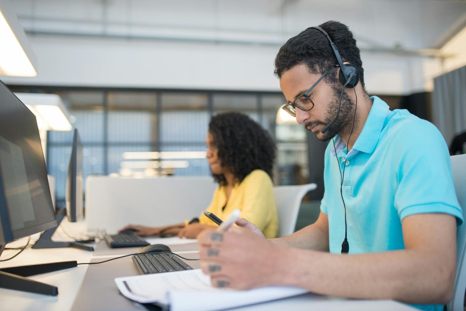 Office employees engaged in productive work at computer stations, enhancing customer service support.