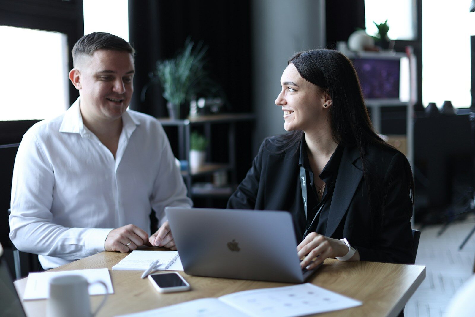 A man and a woman sitting at a table with a laptop