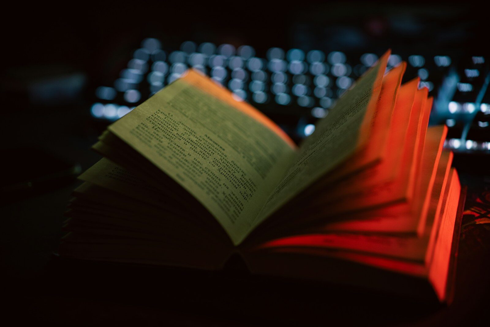 An open book sitting next to a computer keyboard